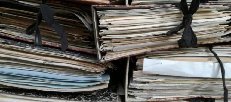 A collection of physical archives in folders tied with black laces