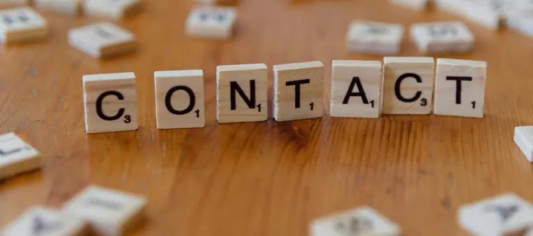 wooden scrable letters spelling contact on a table