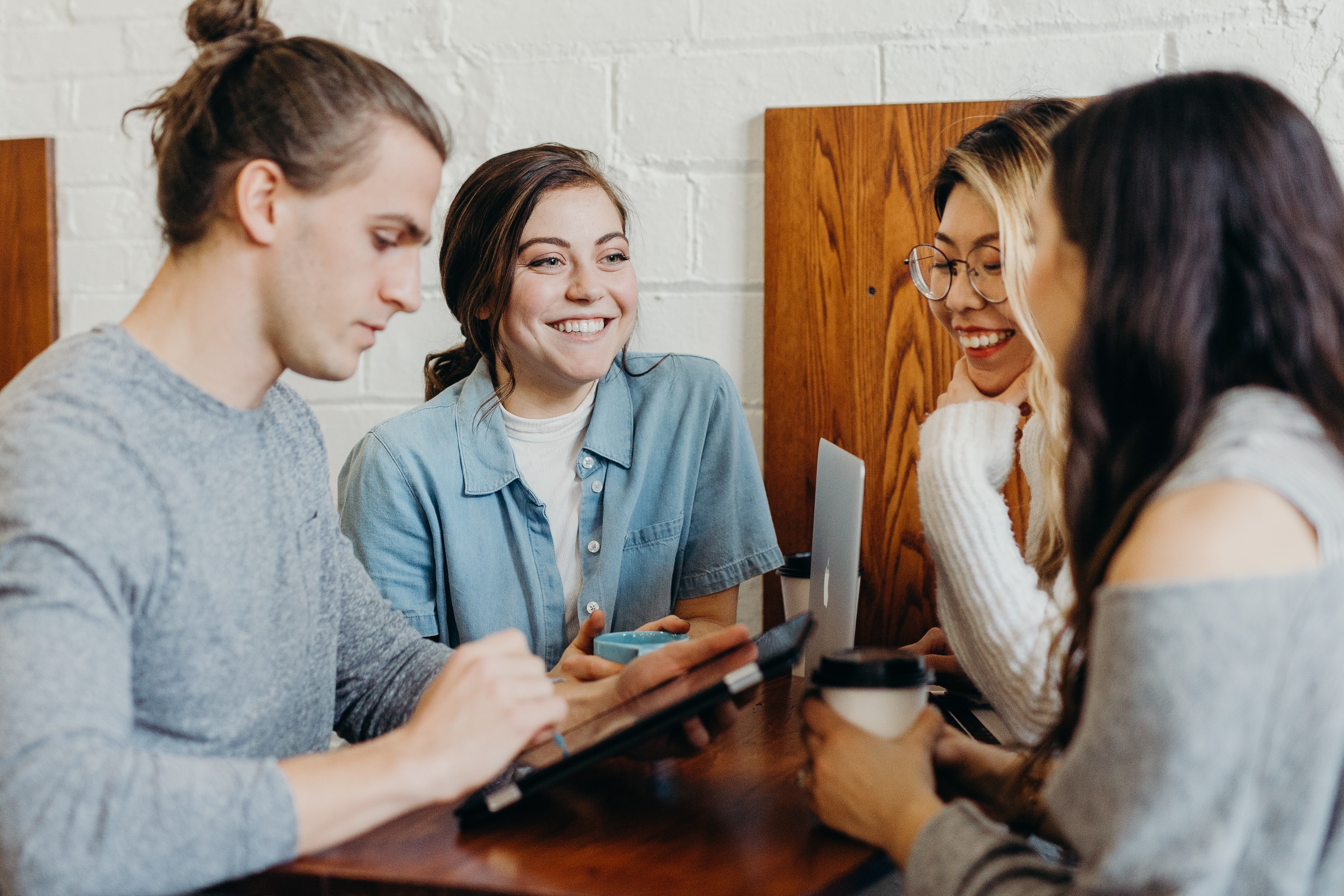 Four students sitting together, having coffee and laughing